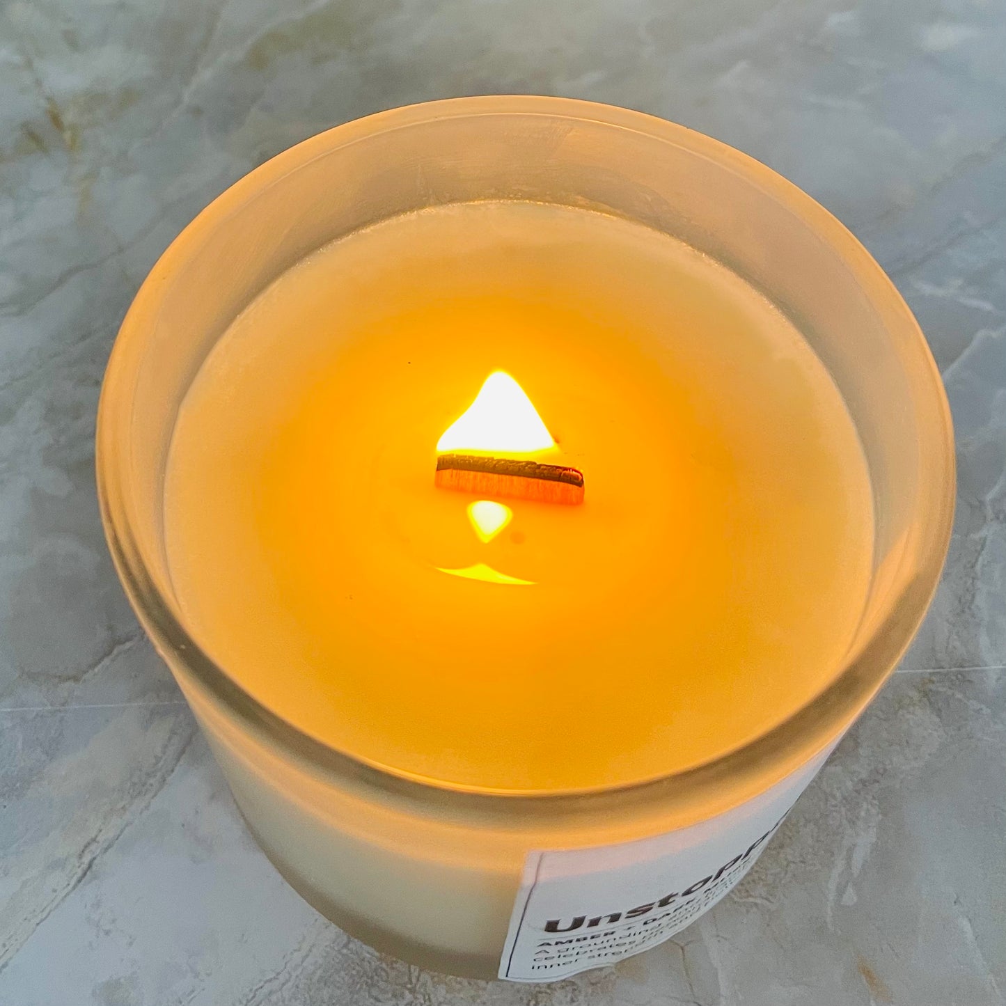 A candle with wooden wick burning with organize flame by studio Vikara