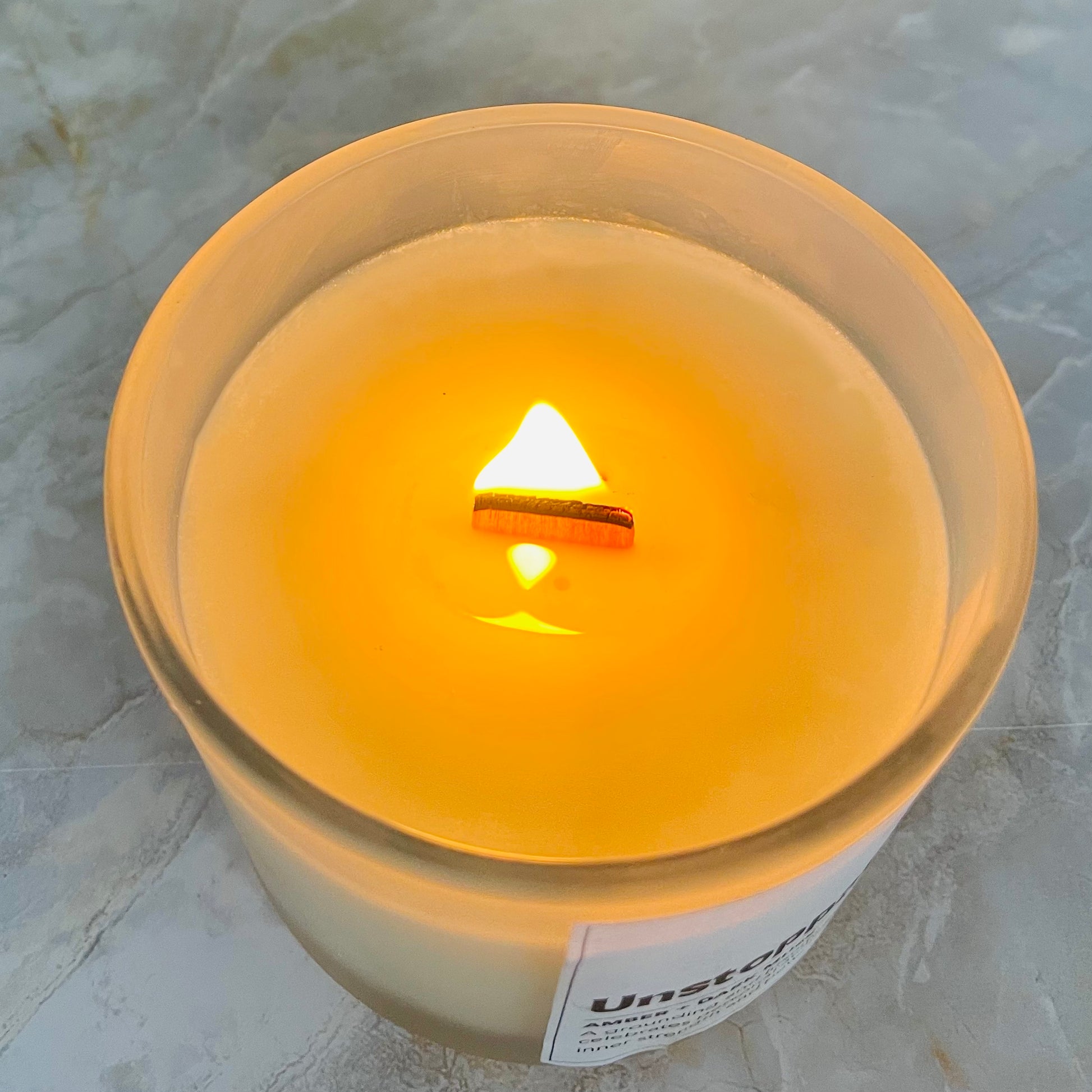 A candle with wooden wick burning with organize flame by studio Vikara 