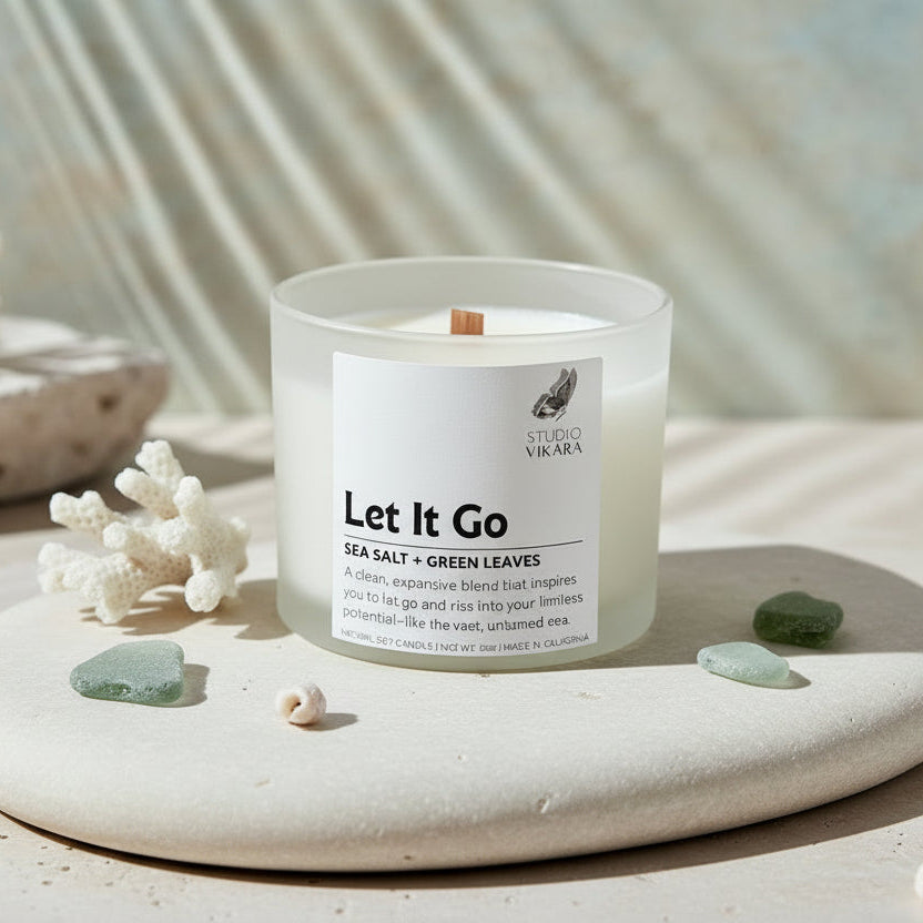 Candle with a label reading 'Let It Go' by Studio Vikara on a beige background