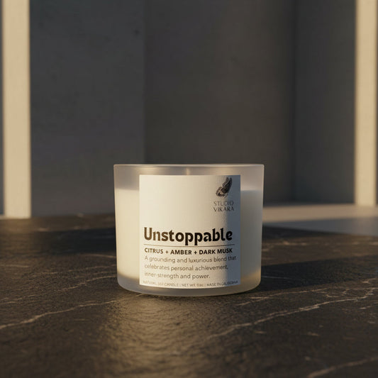 Candle labeled 'Unstoppable' on a dark surface with a neutral background